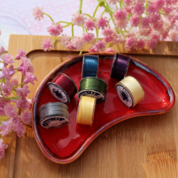 Kolorowe gładkie nici toho nawinięte na małe szpulki.